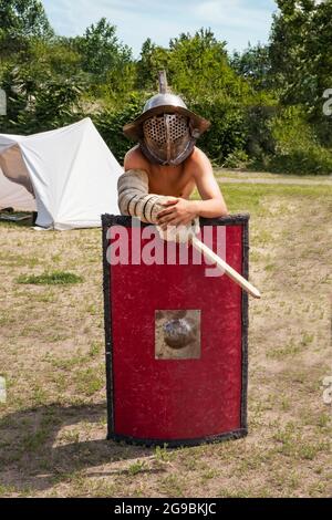 Un jeune homme dans un casque et protection de bras se trouve dans le domaine, s'appuyant sur la bataille de bouclier rouge carré au festival des batailles médiévales. K Banque D'Images