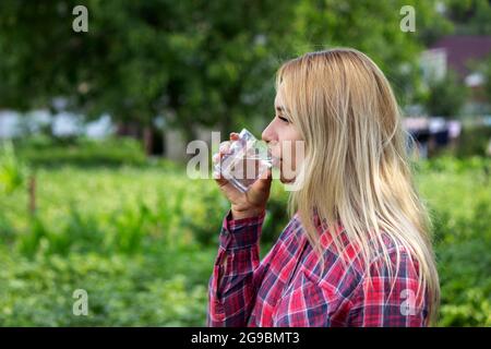 une fille boit de l'eau depuis un verre, à l'extérieur. Mise au point sélective Banque D'Images