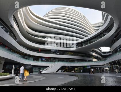 Pékin, Chine. 25 juillet 2021. Les gens marchent près du centre commercial de la galaxie SOHO à Beijing. Le Galaxy SOHO est situé dans la 2ème route du périphérique est, près de Chaoyangmen, Beijing. Il a été achevé en 2012 et construit par Zaha Hadid Architects, Royaume-Uni, couvrant une superficie de 334000 mètres carrés (3595000 pieds carrés). (Photo de Sheldon Cooper/SOPA Images/Sipa USA) crédit: SIPA USA/Alay Live News Banque D'Images