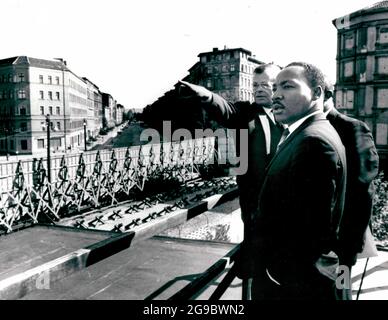 Allemagne, Berlin -- Dr. Martin Luther King à la frontière du secteur soviétique du mur dans la Bernauer Strasse. Herr Werner Steltzer, directeur du Centre d'information de Berlin, indique des points d'intérêt, 1964