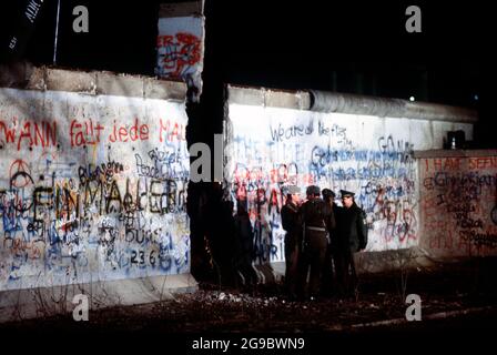 Les gardes allemands de l'est et de l'Ouest se concoupent à l'ouverture nouvellement créée dans le mur de Berlin après qu'une grue a enlevé une section de la structure à côté de la porte de Brandebourg, 1989 Banque D'Images