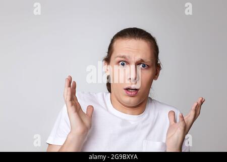 homme effrayé dans un t-shirt isolé sur fond gris. Banque D'Images