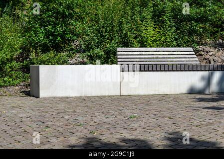 Un banc en béton avec un siège en bois debout dans le parc près du trottoir. Banque D'Images