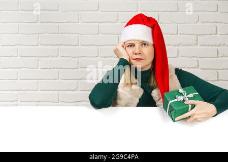 femme dans un chapeau de gnome rouge et un cadeau dans ses mains Banque D'Images