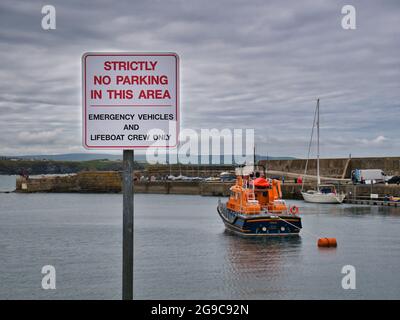 Dans le port de Portrush, en Irlande du Nord, un panneau avec texte rouge sur fond blanc indique qu'aucun stationnement n'est autorisé, sauf pour les véhicules d'urgence Banque D'Images