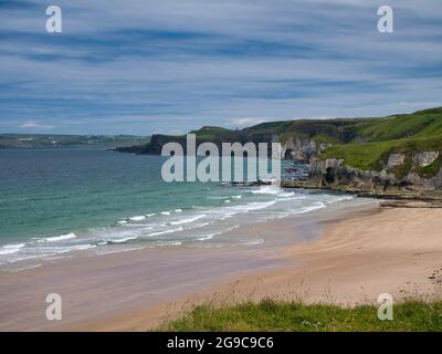 Le sable immaculé de la plage de Whiterocks et les falaises côtières de la côte d'Antrim Causeway en Irlande du Nord, au Royaume-Uni. Pris par une journée ensoleillée en été avec lig Banque D'Images