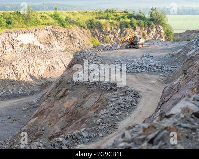 Pelle hydraulique industrielle à chaînes creusant sur un site de carrière, machines lourdes. Route sale dans une fosse ouverte Banque D'Images