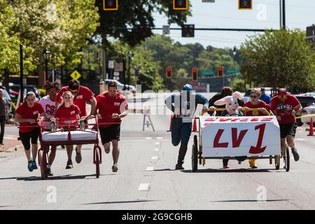 Lawrenceville, GA, États-Unis - 27 avril 2019 : deux équipes poussent des lits faits maison sur des roues dans une rue dans une course de lit pour profiter à la charité. Banque D'Images