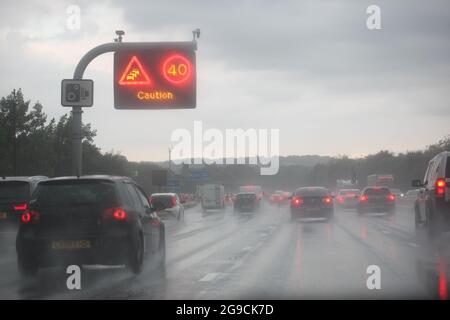 Voitures roulant dans des conditions météorologiques humides avec des réductions de vitesse en place et circulation en file d'attente Banque D'Images