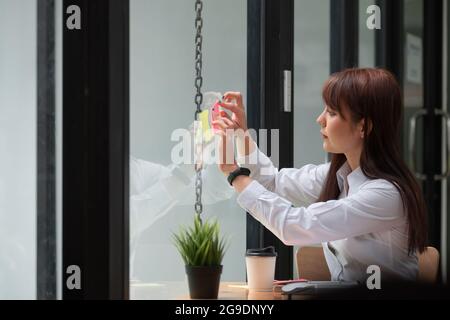 Femme d'affaires publier des notes d'idée discuter et la planification dans mur de verre, Business Financial concept. Banque D'Images