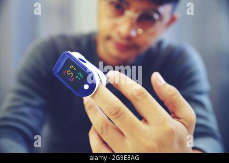 Homme mesurant son propre oxygène à l'aide d'un oxymètre de pouls FingerTIP. Placez la sonde sur le doigt du milieu pour obtenir la mesure la plus précise possible.sélectionnez un Banque D'Images