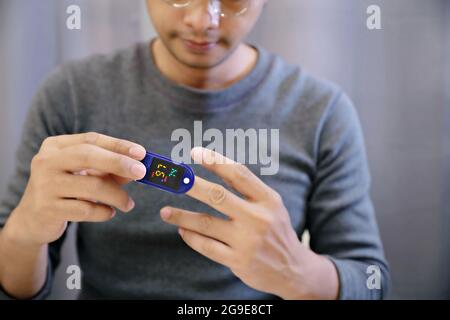 Homme mesurant son propre oxygène à l'aide d'un oxymètre de pouls FingerTIP. Placez la sonde sur le doigt du milieu pour obtenir la mesure la plus précise possible.sélectionnez un Banque D'Images