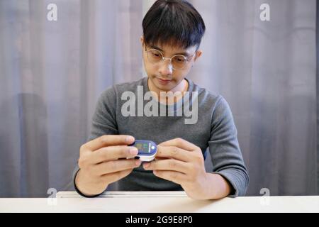 Homme mesurant son propre oxygène à l'aide d'un oxymètre de pouls FingerTIP. Placez la sonde sur le doigt du milieu pour obtenir la mesure la plus précise possible.sélectionnez un Banque D'Images