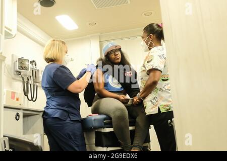 Les travailleurs de la santé du département de santé de Detroit administrent une dose du vaccin Covid-19 de Pfizer à un patient pendant la clinique mobile de vaccination à l'East English Village High School. Les cliniques de vaccination ont lieu à diverses dates jusqu'au reste du mois de juillet et jusqu'en août dans 3 écoles secondaires publiques différentes à Detroit, Michigan. Les cliniques font partie d'un effort entre le département de santé de Detroit et le district communautaire des écoles publiques de Detroit pour administrer autant de vaccins qu'ils peuvent avant l'année scolaire à venir, et pour essayer de réduire le nombre croissant de cas de Covid variant de Delta Banque D'Images