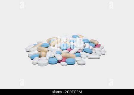 Pile de pilules et capsules de couleur bleue, blanche, rose et jaune sur fond blanc Banque D'Images