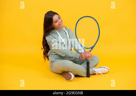 une jeune fille gaie dans des vêtements de sport tient des raquettes de tennis sur fond jaune, sport Banque D'Images