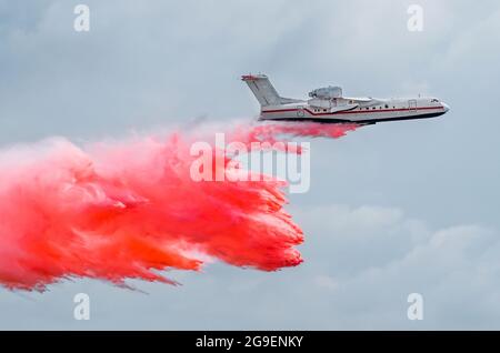 Un avion de pompier jette de l'eau rouge sur un feu dans la forêt Banque D'Images