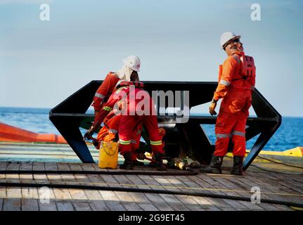 l'équipe maritime travaille sur le pont pendant l'opération de manutention de fret pour soulever l'engin en mer Banque D'Images