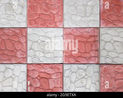 revêtement en béton de couleur grise et rouge. Trottoir de pavés gris et rose en gros plan. Texture, fond de pierre gris-orange curly. Vue de dessus sur le Banque D'Images