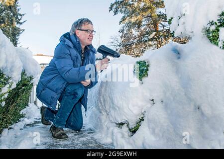 Météo, l'homme souffle la neige à l'extérieur, avec sèche-cheveux, Munich, Bavière, Allemagne, FÉVRIER 2019, DROITS-SUPPLÉMENTAIRES-AUTORISATION-INFO-NON-DISPONIBLE Banque D'Images