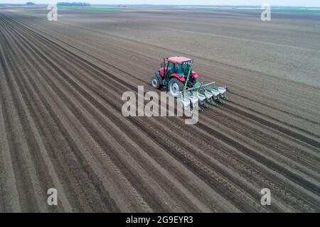 Image aérienne du tracteur semant avec l'équipement des bacs à semences dans le champ au printemps Banque D'Images