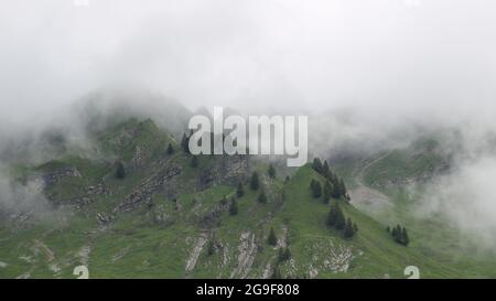 Scène estivale dans les Alpes suisses par un jour pluvieux et brumeux. Prés verdoyants et crête de montagne. Banque D'Images