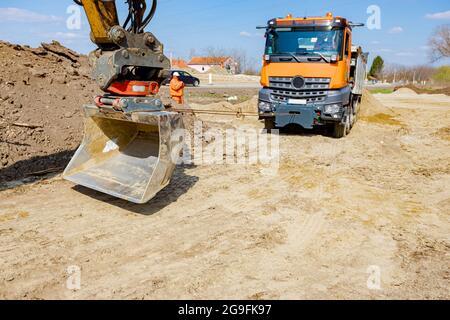 Une pelle tire un camion benne avec un cordon pour l'aider à sortir du sable sur le chantier. Banque D'Images
