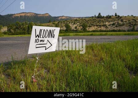 Un signe blanc fait à la main avec des lettres noires placé le long d'un tronçon éloigné de l'autoroute marque le chemin d'un mariage, près de Pagosa Springs, Colorado, États-Unis. Banque D'Images
