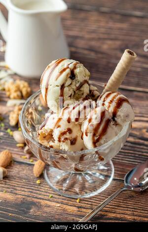 Glace Roma aux amandes, pistaches et noix dans un bol en verre avec sauce caramel. Banque D'Images