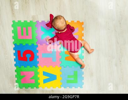 Bonne petite fille fluage sur la moquette avec des lettres Banque D'Images