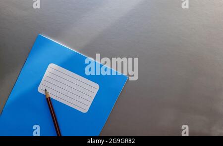 Nouveau carnet bleu avec crayon sur une table grise avec rayons de soleil depuis l'arrière-plan de la fenêtre. Banque D'Images