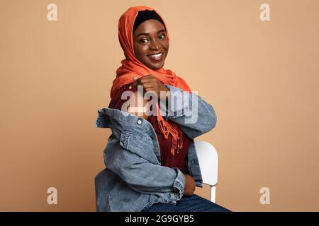 Une jeune femme noire musulmane dans le hijab s'est vaccinée, souriante femme afro-américaine montrant l'épaule avec un groupe médical sur, fond beige studio, Banque D'Images