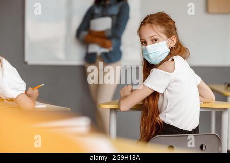 Jolie fille assise à son bureau à l'école Banque D'Images