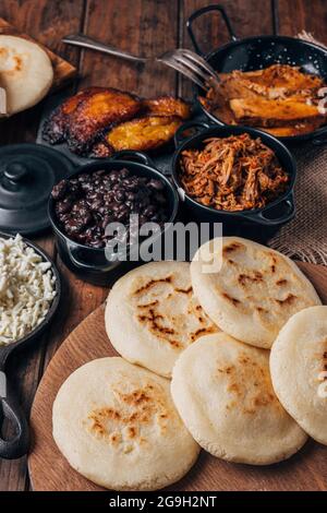 Table servie avec petit déjeuner vénézuélien, arepas avec différents types de garnitures telles que caraotas, carne mechada, pernil, plantain frit et fromage Banque D'Images