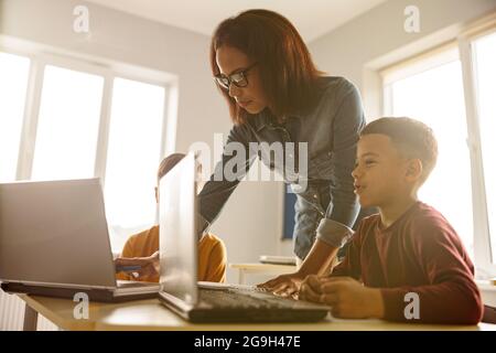 Enseignante en lunettes et écoliers pendant la leçon en classe Banque D'Images
