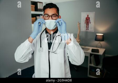 Race mixte homme médecin travaillant dans le bureau portant un masque chirurgical Banque D'Images