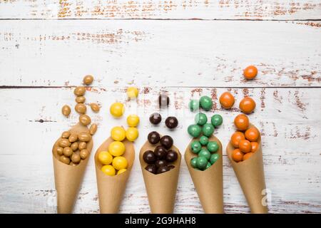 Différentes saveurs de pralines au chocolat dans des cônes en papier sur une table en bois. Banque D'Images