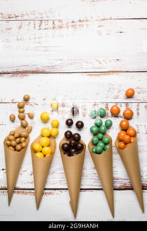 Différentes saveurs de pralines au chocolat dans des cônes en papier sur une table en bois. Banque D'Images