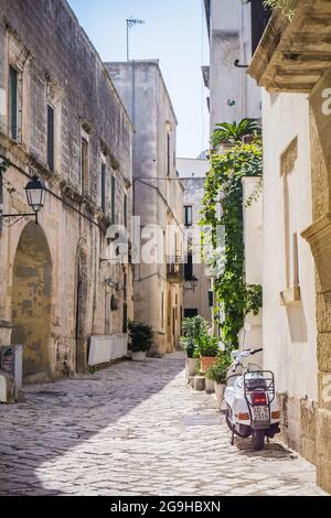 Otranto, Italie - 6 septembre 2017 : belles rues étroites et typiques de la vieille ville d'Otranto, Italie, Apulia. Scooter blanc stationné dans la rue. Pas de personne, jour ensoleillé. Banque D'Images