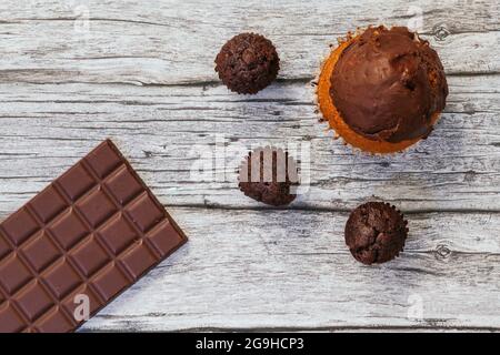 Vu d'en haut, sur quelques planches en bois il y a un grand cupcake avec garniture au chocolat, il y a aussi trois petits cupcakes au chocolat et un Choco foncé Banque D'Images