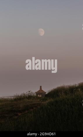 Une incroyable lune qui s'élève au-dessus d'une maison de bateau dans les dunes de sable Banque D'Images