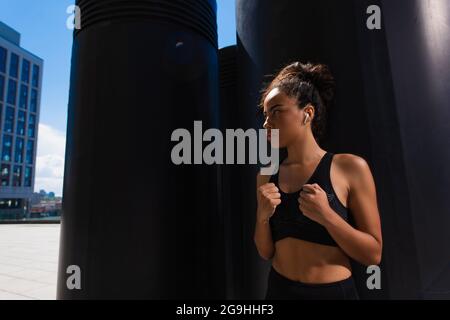 African american sportswoman dans les écouteurs regardant la rue urbaine la journée Banque D'Images