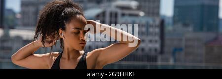 African american sportswoman dans les écouteurs s'étendant à l'extérieur, bannière Banque D'Images