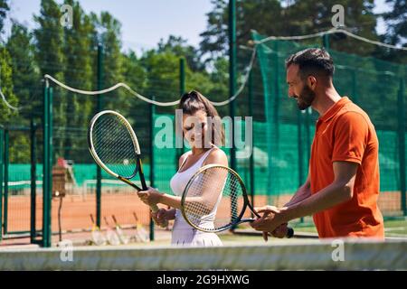 Instructeur montrant une bonne technique de manche de tennis à son client Banque D'Images
