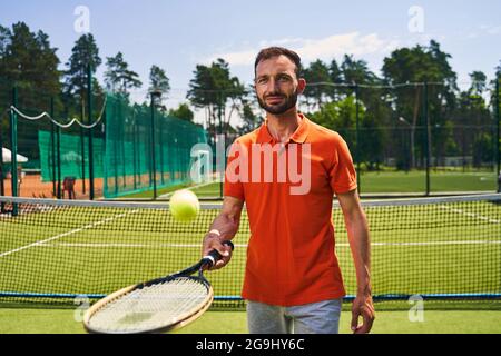 Débutant joueur de tennis masculin maîtrisant la technique de service Banque D'Images