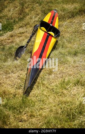 Le kayak unique, peint en couleurs de drapeau allemand, sèche sur l'herbe après la compétition. Paddle est à côté. Gros plan. Mise au point sélective. Banque D'Images