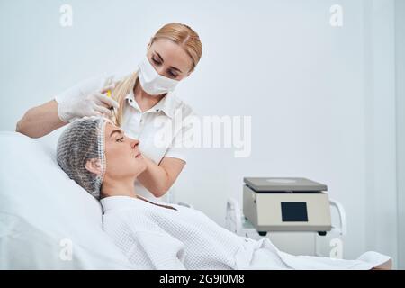 Jeune travailleur médical compétent qui effectue un traitement de mésothérapie Banque D'Images