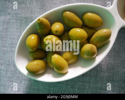 Dose d'olives vertes fraîches dans un bol blanc Banque D'Images