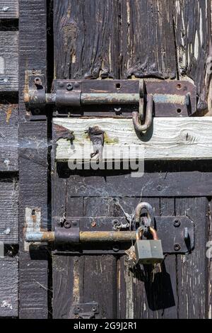 les anciennes serrures de porte moraillent et agrafent les boulons de glissière sur la porte de la grange ou du hangar extérieur. le temps a battu les anciennes serrures sur la porte du hangar en bois. hangar à cadenas ou cabine de jardin Banque D'Images