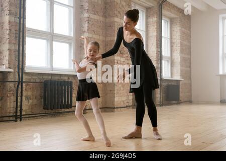 Petite fille apprenant à se tenir dans la bonne position pendant elle cours de ballet avec entraîneur Banque D'Images